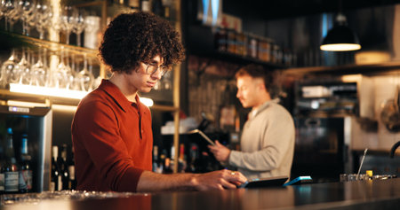 Business, man and bartender in restaurant, tablet and digital app for inventory, counter and internet. People, employees and hospitality with technology, alcohol or customer service with drinks orderの写真素材