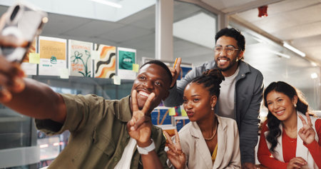 Happy people, group or peace sign with selfie for photography, picture or memory in office. Excited, employees or creative colleagues with smile or emoji for capture moment or friendship in workplaceの写真素材