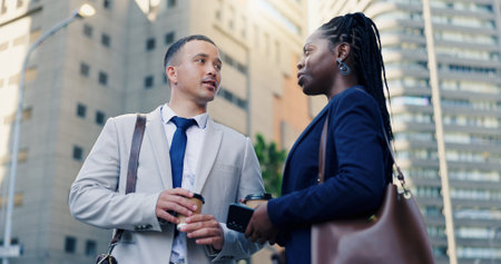 Colleagues, talking and travel to work, city and conversation for case with coffee or collaboration. Outdoor, attorney and people with latte on street, low angle and discussion for trial or commutingの写真素材