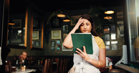 Waitress, stress or woman at cafe with tablet for inflation, bankruptcy or financial crisis. Sad, headache or barista at coffee shop with mistake, fail or reading bad review on social media with techの写真素材