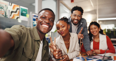 Happy people, portrait or creative group with selfie for photography, picture or memory in office. Face, employees or colleagues with smile or peace sign for capture moment or friendship in workplaceの写真素材