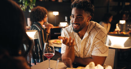Happy man, night or date with chat in restaurant for fine dining, dinner or anniversary. Male person, talking and smile with couple in conversation for romance, valentines day or evening out togetherの写真素材