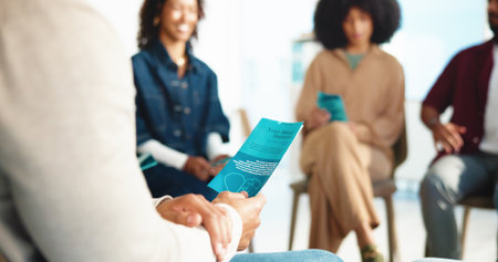 Documents, people and support with mental health, hands and feedback in meeting. Group, pamphlet and men with women, discussion and information with wellness, stress relief and psychology with helpの写真素材