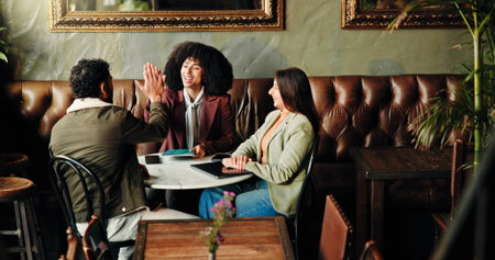 Meeting, high five and business people in coffee shop for discussion on proofreading for publishing. Happy, celebration and female editors with author for book research success in restaurant or cafe.の写真素材