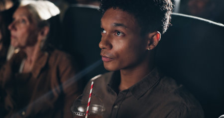 Movie theater, audience and man with drink, premiere or reaction for entertainment, dark or weekend. Watching, film and person with beverage for break, cinema and spectator at night and projectionの写真素材