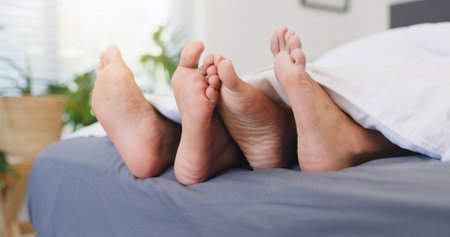 Sleeping, couple and feet on bed, home or comfortable in bedroom, relationship or together on break. Barefoot, people and rest on mattress in house, relax and free time on weekend, legs and apartmentの写真素材