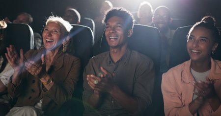 Applause, happy and audience in theatre for movie, comedy show and reaction for film in cinema. Laughing, entertainment and group of men and women for motion picture, premiere success and approvalの写真素材