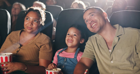 Family movie, theatre and child with popcorn in cinema for entertainment, experience and watching cartoon. Happy, parents and girl with snacks for screening, animation or film audience for productionの写真素材