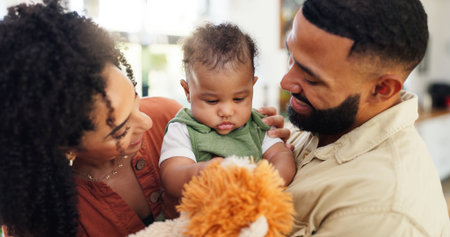 Home, baby and parents with teddy bear, love and bonding together with happiness, care and playful. Apartment, family or mother with father, infant and fluffy toy with connection or child developmentの写真素材