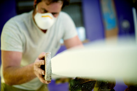 Sanding, workshop or man with engineering project for manufacturing furniture or surfing equipment. Creative, small business or worker in labor production process for building surfboard in warehouseの写真素材