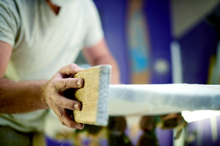 Man, hands and sanding surfboard in workshop for craft, inspection or quality control. Hobby, surfer or tools in studio for maintenance, equipment shaping and entrepreneur with small business serviceの写真素材