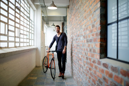 Man, hallway or travel with bicycle to apartment for local commute, transportation or cycling trip. Male person, tourist or moving with bike in corridor or building for journey or eco friendly rideの写真素材