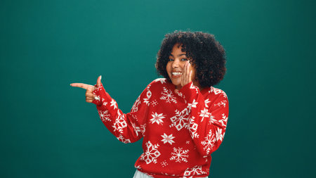 Christmas, pointing and whisper with portrait of woman in studio for holiday season, celebration and promotion. Festive deals, xmas and announcement with person on green background space with mockupの写真素材