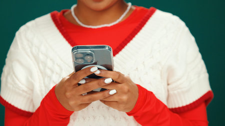 Christmas, phone and hands of woman in studio with networking, communication or social media....