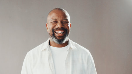 Happy, professional and portrait of black man in studio with confidence for finance career development. Smile, male person and mature African financial advisor with pride for job by gray background.の写真素材