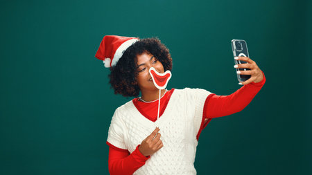 Woman, Christmas and happy for selfie in studio with lips, emoji or hat with mockup space on background. Person, influencer and smile for photography, profile picture or social media for xmas holidayの写真素材
