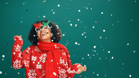 Confetti, Christmas and woman in studio dance for party, festive season and holiday. Mockup space, December and person with decoration, glitter and energy for xmas celebration on green backgroundの写真素材