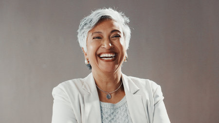 Laugh, professional and portrait of businesswoman in studio with confidence for finance career development. Happy, female person and mature financial advisor from Mexico with pride by gray backgroundの写真素材