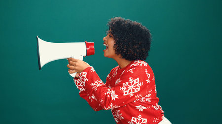 Woman, Christmas and shout with loudspeaker in studio, happy and profile with announcement on background. Girl, smile and festive celebration with xmas sale, bullhorn and holiday season with voiceの写真素材