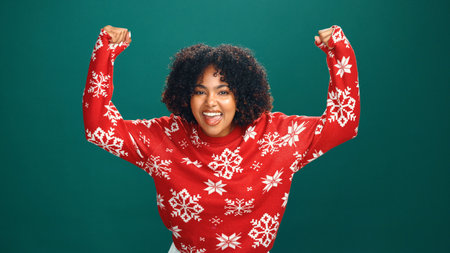 Christmas, excited and portrait of black woman in studio for tradition, festive or celebration. Happy, cheering and face of African female person with good news for xmas party by green background.の写真素材