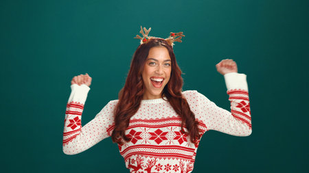 Christmas, happy and portrait of woman with dance in studio for tradition, festive or celebrate. Smile, antlers and face of female person from Colombia with rhythm for xmas party by green background.の写真素材