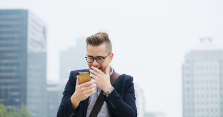 Shocked, phone and businessman in city with good news, email or job promotion with happiness. Smile, surprise and male financial manager with cellphone for investment approval in urban town.の写真素材