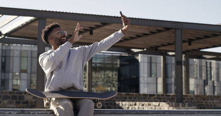 Man, skateboard and selfie with smile, outdoor and relax with training, live streaming and practice. City, skater or person with profile picture, happy or influencer with exercise or content creationの写真素材