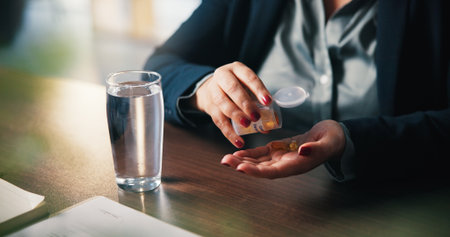 Water, pills and hands of woman in home for medical treatment, prescription and tablets for recovery. House, health and person with medication container for vitamins, supplements and drugs on tableの写真素材