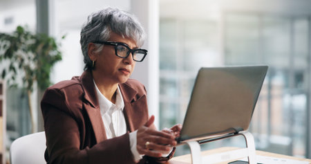 Business, laptop and woman in office, online reading and creative agency with email. Mature person, employee and fashion journalist in workplace, PC and magazine editor with review and news reportの写真素材