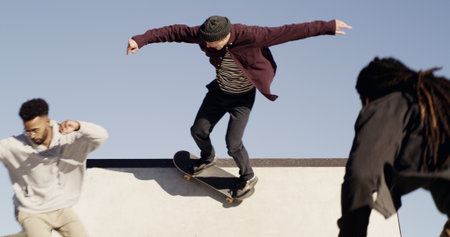 Men, skateboard and friends on ramp at park with trick, outdoor and culture with streetwear in city. People, skater group and training with balance, hobby and low angle with sky for extreme sportsの写真素材