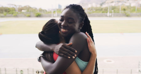 Friends, hug and runners in stadium for fitness, summer marathon and endurance. Women, athlete and smile for teamwork, collaboration and outdoor for wellness and exercise on running track togetherの写真素材
