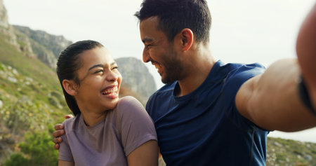 Couple, selfie and smile for hiking on mountain, hug and laugh with live stream for adventure in nature. Happy woman, man and photography for memory, care or social media for trekking in Colombiaの写真素材