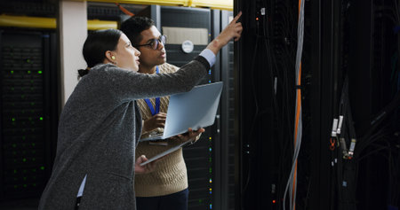 People, laptop and tablet with teamwork in server room for technical support, software update or maintenance. Inspection, upgrade and work together for information technology solution in data centerの写真素材