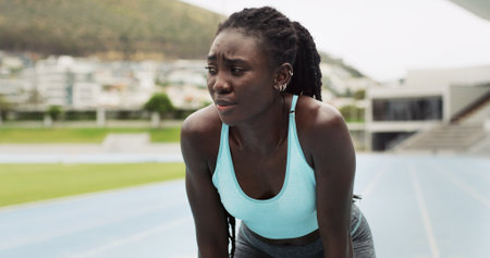 Fitness, tired and thinking with black woman in stadium for workout fatigue, marathon endurance and sports. Exhausted, cardio challenge and training with person on race track for vision and athleteの写真素材