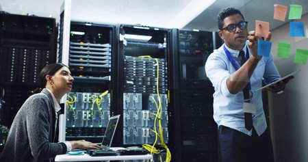 People, technician and planning with sticky note in server room for priority on network security. IT...