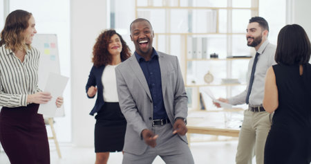 Dance, happy and businessman with team in office with good news, promotion and success. Corporate, professional and workers celebrate together for teamwork, collaboration and company achievementの写真素材