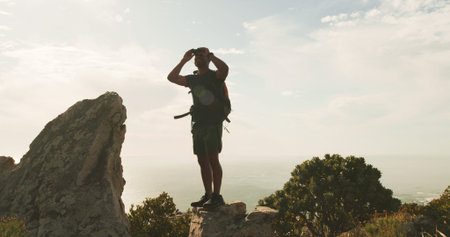 Man, binoculars and hiking on mountain, sky and smile for sightseeing, birdwatching or adventure....