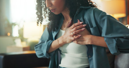 Heart attack, emergency and fear with woman on sofa for chest pain, angina and medical crisis. Cardiac arrest, hypertension and anxiety with person in living room of home for heartburn and riskの写真素材