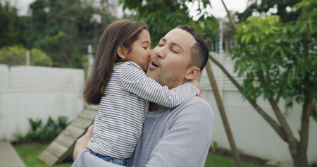 Kiss, happy and dad with girl in backyard for bonding, affection and relax outdoor on weekend. Family, love and father with child for embrace, hug or connection together for support, care and playfulの写真素材