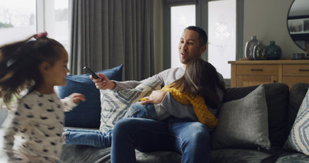 Watching TV, playing and dad with children on sofa for chaos, running and relaxing in home. Family, living room and father with remote for entertainment, cartoons and movies with energetic kidsの写真素材