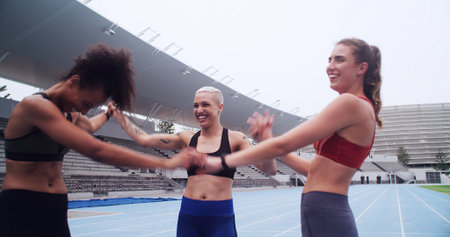 Woman, athlete and holding hands in huddle, team and excited with celebration for achievement on track. People, girl and happy with motivation, goals or support in circle for sports training at arenaの写真素材