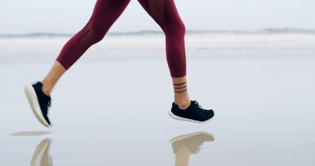 Running, legs and fitness with woman at beach for health, cardio workout and sports training. Marathon practice, exercise and runner challenge with person outdoor for energy, athlete and wellnessの写真素材