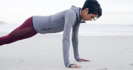 Athlete, woman and pushup for exercise by ocean for fitness, strength training and strong muscles....