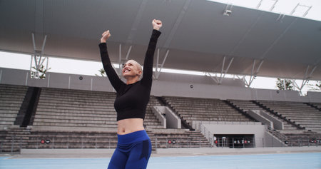 Excited, athlete and woman at stadium, success or cheering for complete fitness goal or celebration. Outdoor, runner and person with smile for achievement, training and exercise for marathon or sportの写真素材
