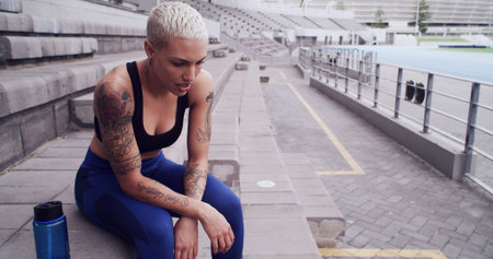 Runner, woman and tired with breathing at stadium for running recovery, overworked and resting....