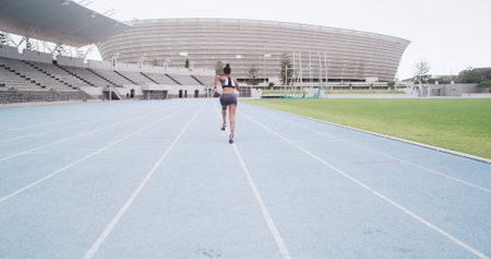 Back, stadium and woman running for sports, exercise and practice for fitness outdoor. Race track,...