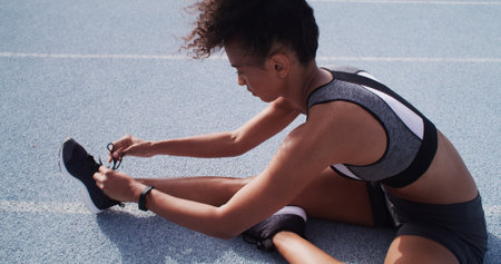 Laces, sneakers and woman on race track for fitness, sports and prepare for practice run outdoor. Female person, runner or athlete with shoes for training, start exercise or workout at stadiumの写真素材