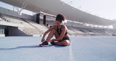 Fitness, stadium and woman tie shoes ready for race challenge, marathon training and exercise. Sports, athlete and person with sneakers for running, competition and cardio workout on outdoor trackの写真素材