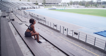 Thinking, athlete and woman relax at stadium for fitness break, planning and exercise ideas. Female...