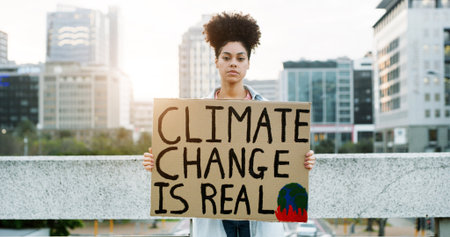 Portrait, woman and protest with billboard in city for awareness, climate change and global warming. Female person, poster sign and stop pollution for planet safety, green movement and society impactの写真素材